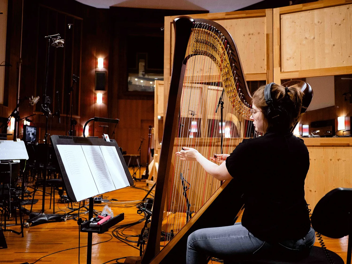 Harpist wearing headphones and playing a concert harp during the BBO Harps recording session at Vienna Synchron Stage.