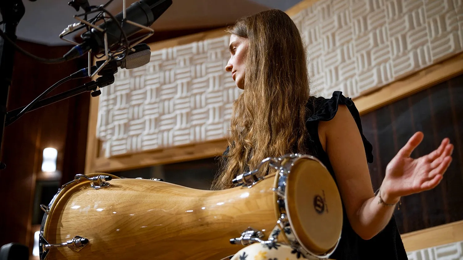 Percussionist playing a batá drum beneath studio microphones at Vienna Synchron Stage